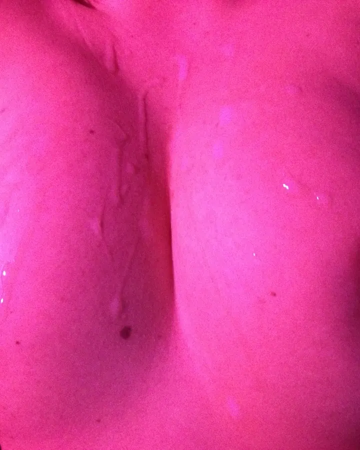 Femme en lingerie noire transparente, prenant un selfie devant un miroir, dans une chambre.